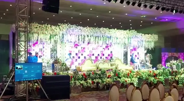 Wedding stage with floral decor, truss lighting and a speaker set to one side